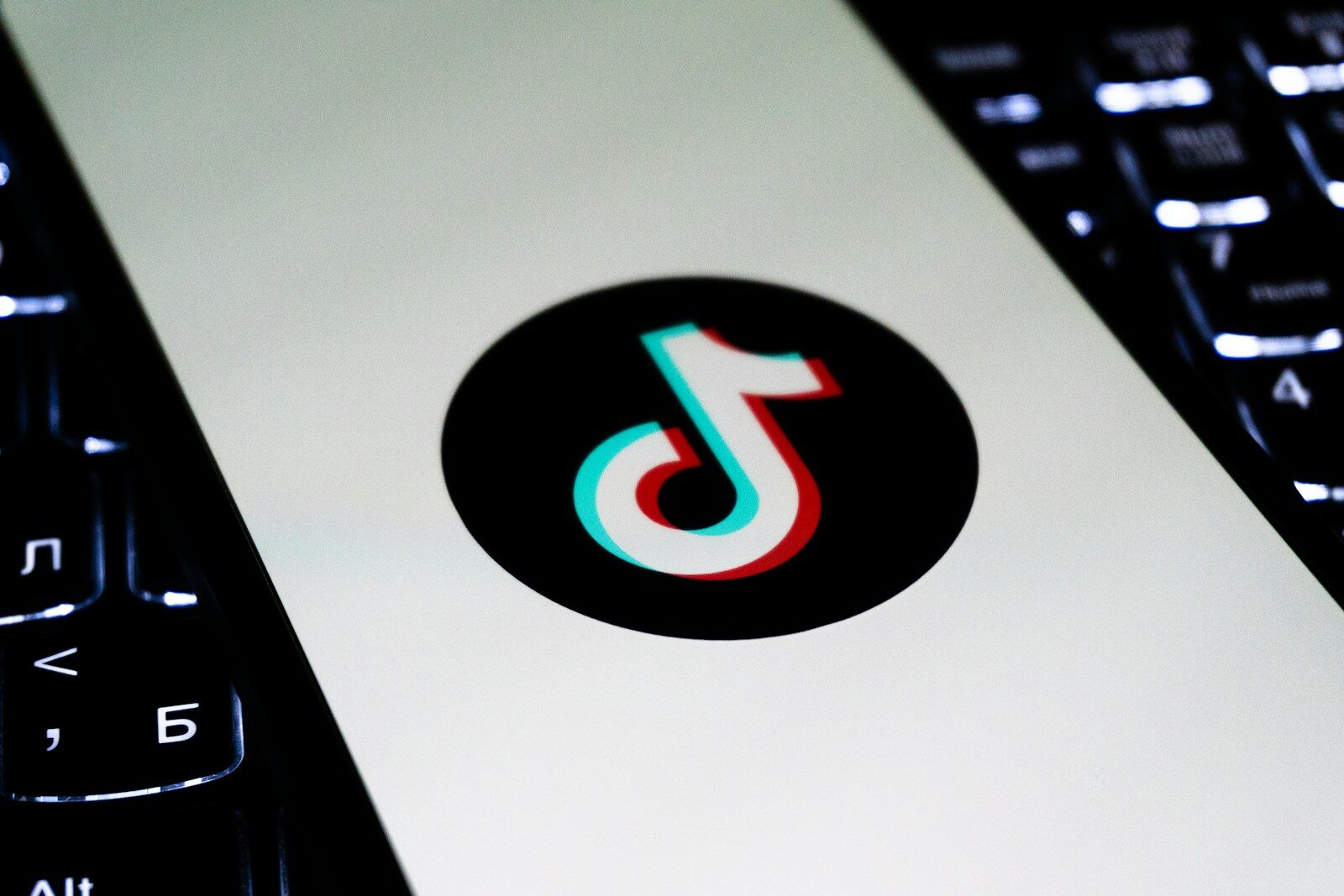 Tiktok logo on a white screen between keyboards