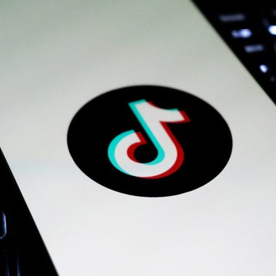 Tiktok logo on a white screen between keyboards